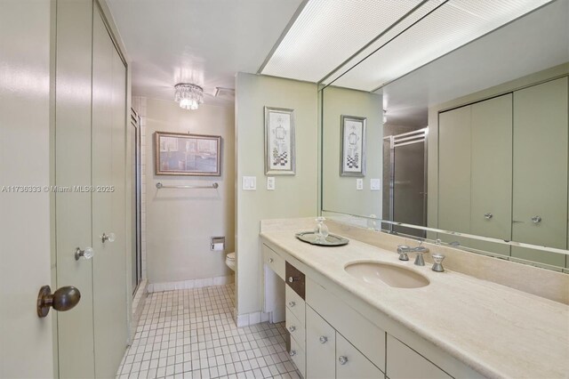 bathroom with tile patterned flooring, vanity, walk in shower, and toilet