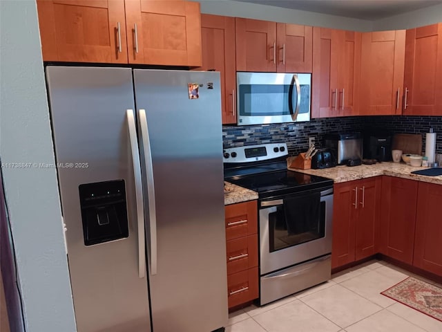 kitchen featuring light stone counters, backsplash, stainless steel appliances, and light tile patterned flooring