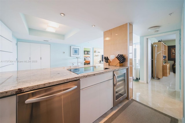 kitchen with a raised ceiling, light stone countertops, beverage cooler, and dishwasher