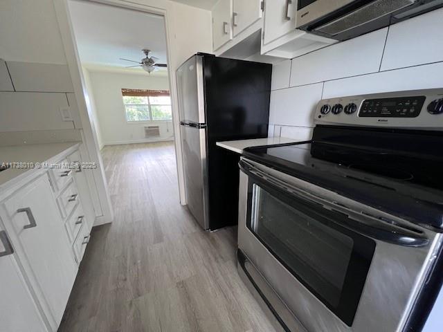 kitchen with white cabinetry, backsplash, ceiling fan, light hardwood / wood-style floors, and stainless steel appliances