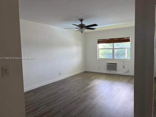 spare room with ceiling fan, dark hardwood / wood-style floors, and an AC wall unit