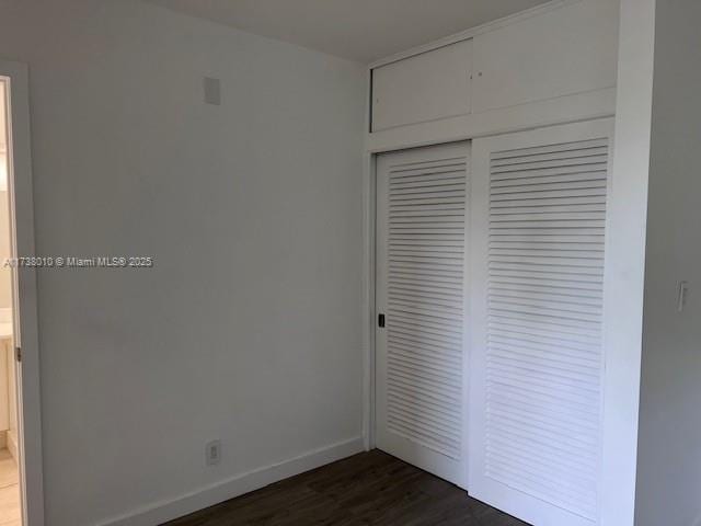 unfurnished bedroom with dark hardwood / wood-style floors and a closet