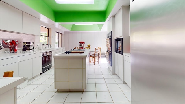 kitchen featuring black double oven, stainless steel gas stovetop, a kitchen island, and white cabinets