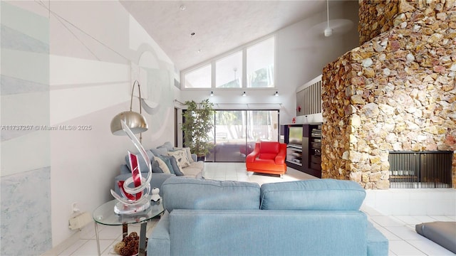 living room featuring a fireplace, high vaulted ceiling, and light tile patterned floors