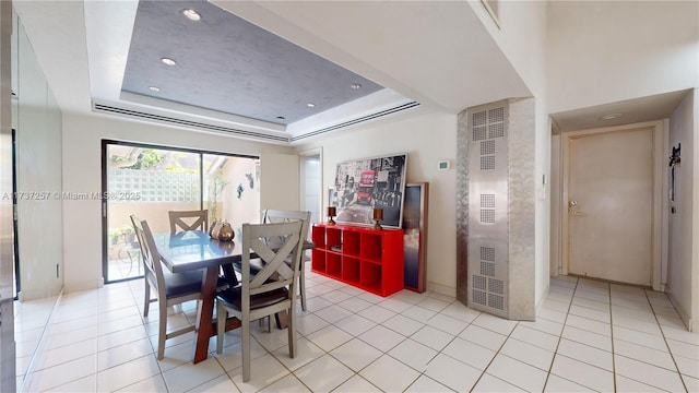 tiled dining area with a tray ceiling