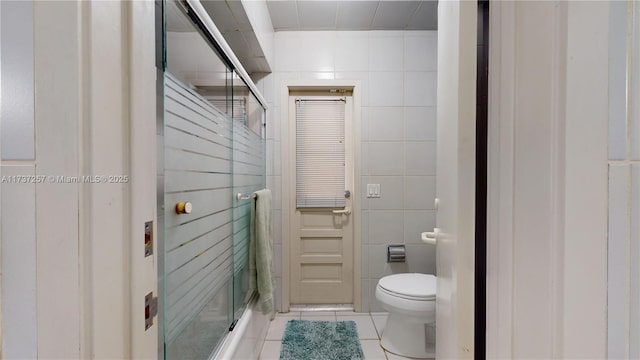 bathroom featuring tile walls, tile patterned flooring, a shower with door, and toilet