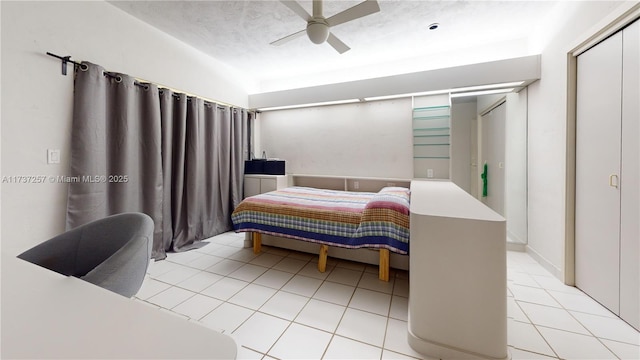 bedroom with ceiling fan, light tile patterned floors, and a textured ceiling