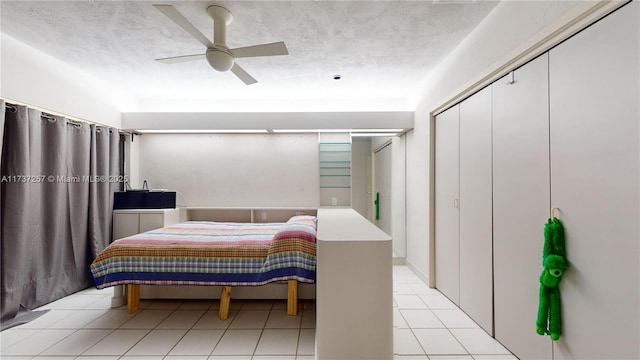 tiled bedroom with ceiling fan, a closet, and a textured ceiling