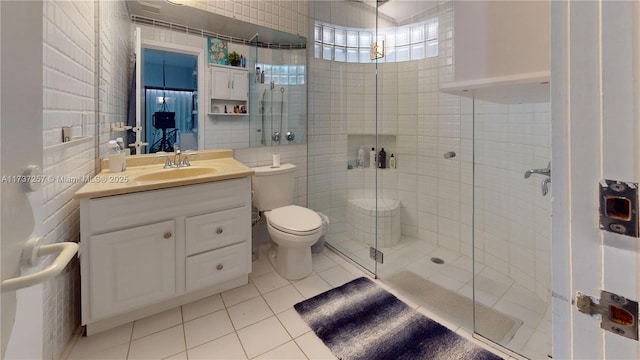 bathroom with tile walls, tile patterned flooring, vanity, walk in shower, and toilet