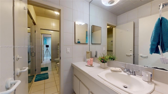 bathroom featuring tile walls, vanity, tile patterned floors, toilet, and walk in shower