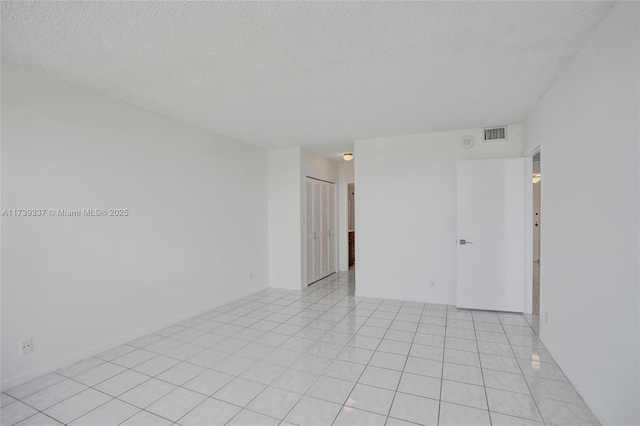 unfurnished room with a textured ceiling and light tile patterned flooring