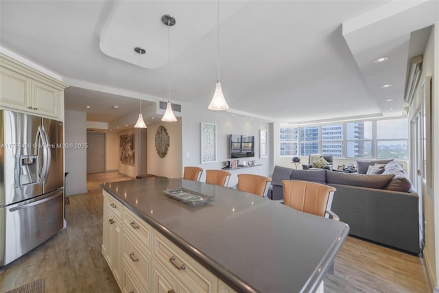 kitchen featuring a kitchen island, pendant lighting, stainless steel refrigerator with ice dispenser, cream cabinets, and light hardwood / wood-style flooring