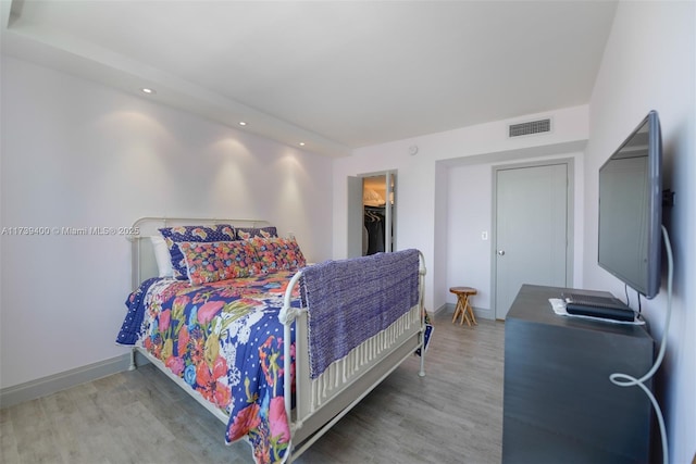 bedroom with hardwood / wood-style flooring and a walk in closet