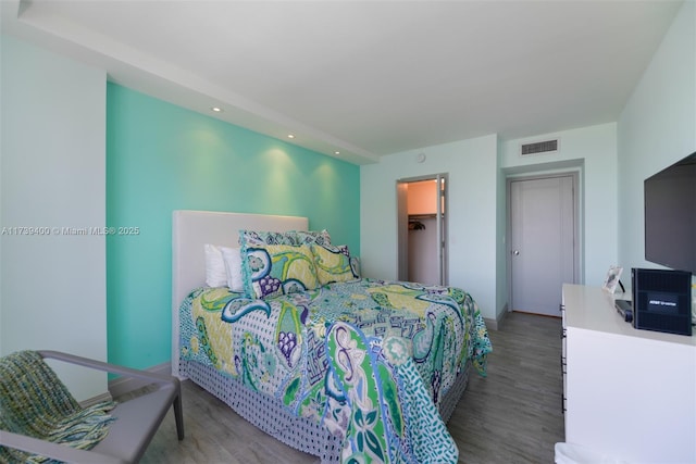 bedroom with a walk in closet and hardwood / wood-style floors