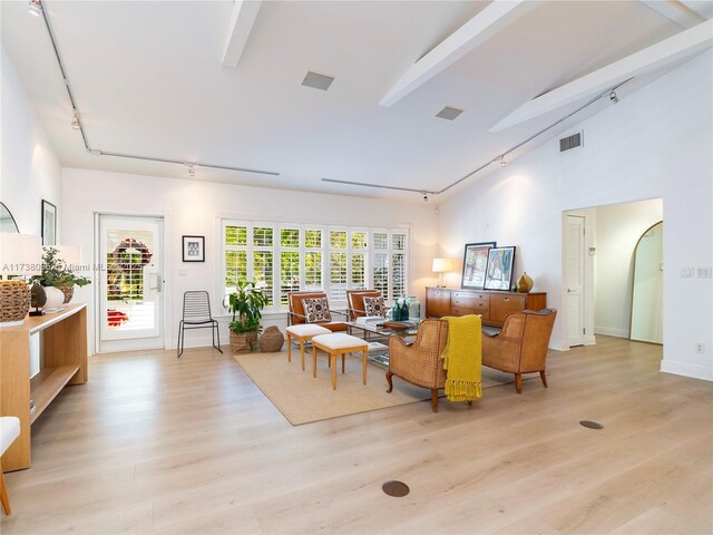 living room featuring light hardwood / wood-style flooring, beam ceiling, and track lighting