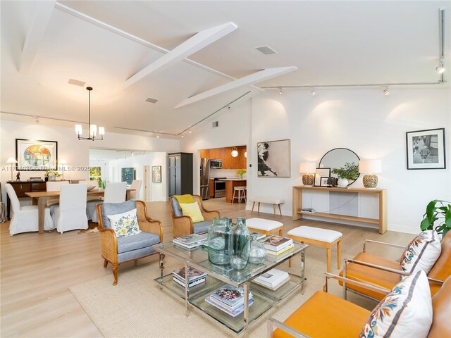 living room featuring rail lighting, an inviting chandelier, high vaulted ceiling, light hardwood / wood-style floors, and beamed ceiling