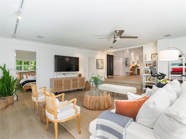 living room featuring rail lighting, hardwood / wood-style floors, and ceiling fan