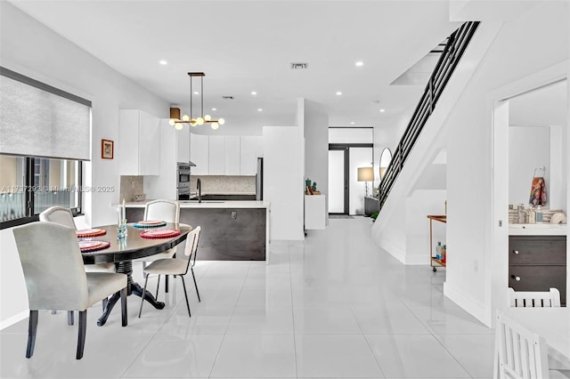 tiled dining room with sink and a chandelier