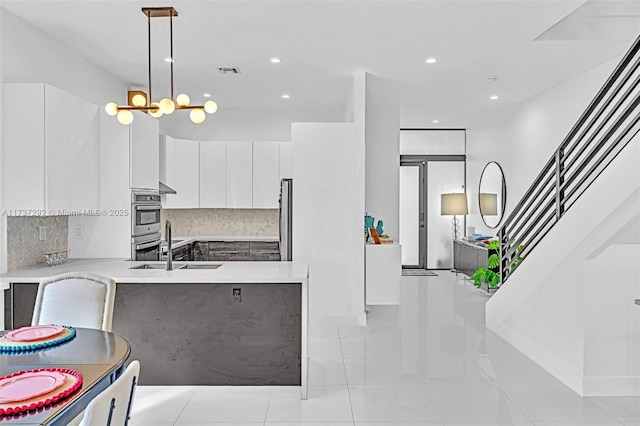 kitchen with white cabinetry, sink, backsplash, hanging light fixtures, and stainless steel appliances