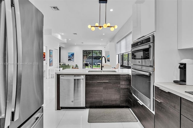 kitchen with stainless steel appliances, sink, white cabinets, and dark brown cabinetry