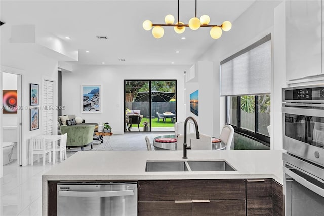 kitchen with sink, dishwasher, dark brown cabinetry, decorative light fixtures, and a chandelier