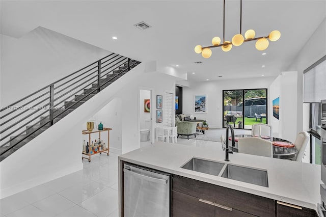 kitchen featuring sink, dishwasher, dark brown cabinetry, decorative light fixtures, and a chandelier