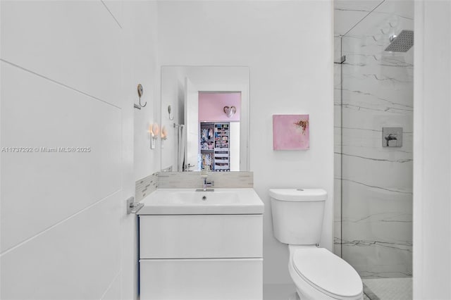 bathroom featuring vanity, toilet, and a tile shower