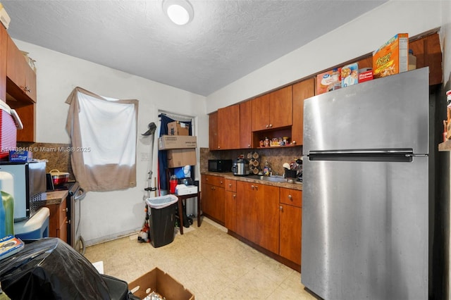 kitchen featuring stainless steel refrigerator, decorative backsplash, and a textured ceiling