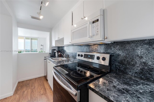 kitchen with appliances with stainless steel finishes, white cabinetry, sink, backsplash, and light hardwood / wood-style flooring