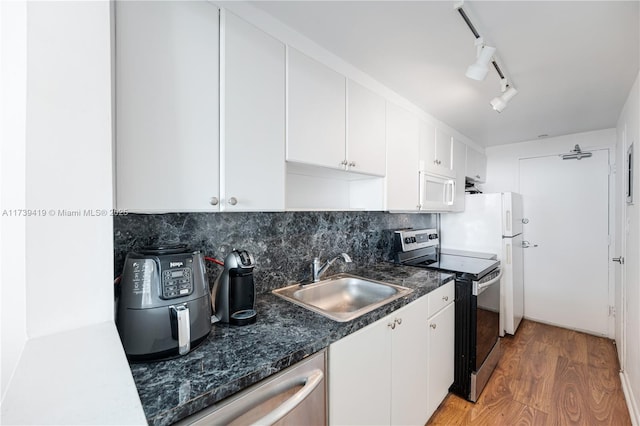 kitchen featuring appliances with stainless steel finishes, tasteful backsplash, white cabinetry, sink, and light hardwood / wood-style flooring