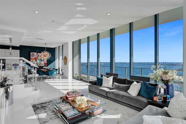 living room featuring an inviting chandelier, floor to ceiling windows, and a water view