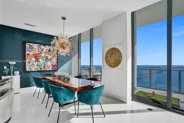 dining space featuring an inviting chandelier, light tile patterned floors, a wall of windows, and a water view