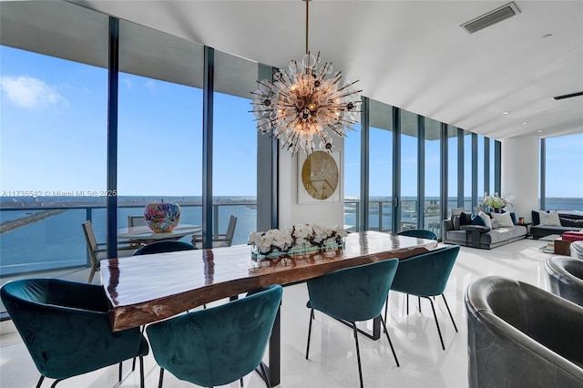 dining area featuring floor to ceiling windows, a chandelier, and a water view