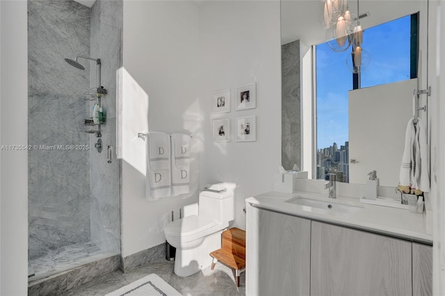 bathroom with tiled shower, vanity, and toilet