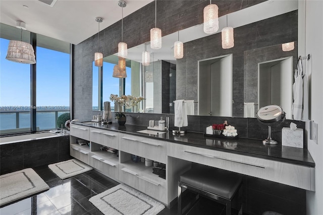 bathroom with tiled tub, vanity, a water view, and tile patterned floors