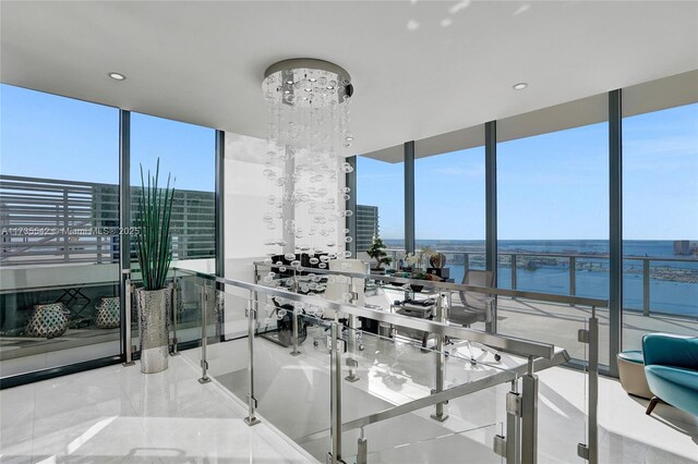 dining room with a notable chandelier, a wall of windows, and a water view