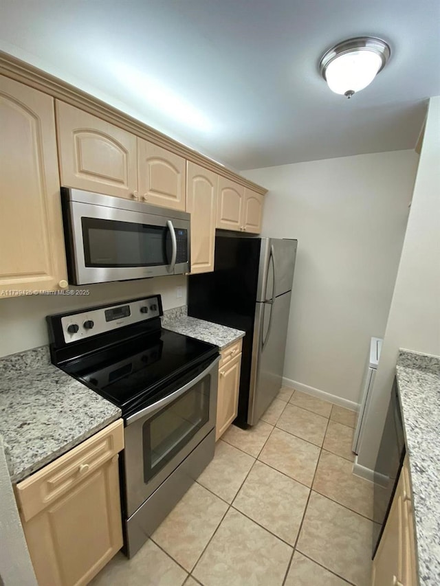 kitchen with light stone counters, appliances with stainless steel finishes, light tile patterned floors, and light brown cabinets