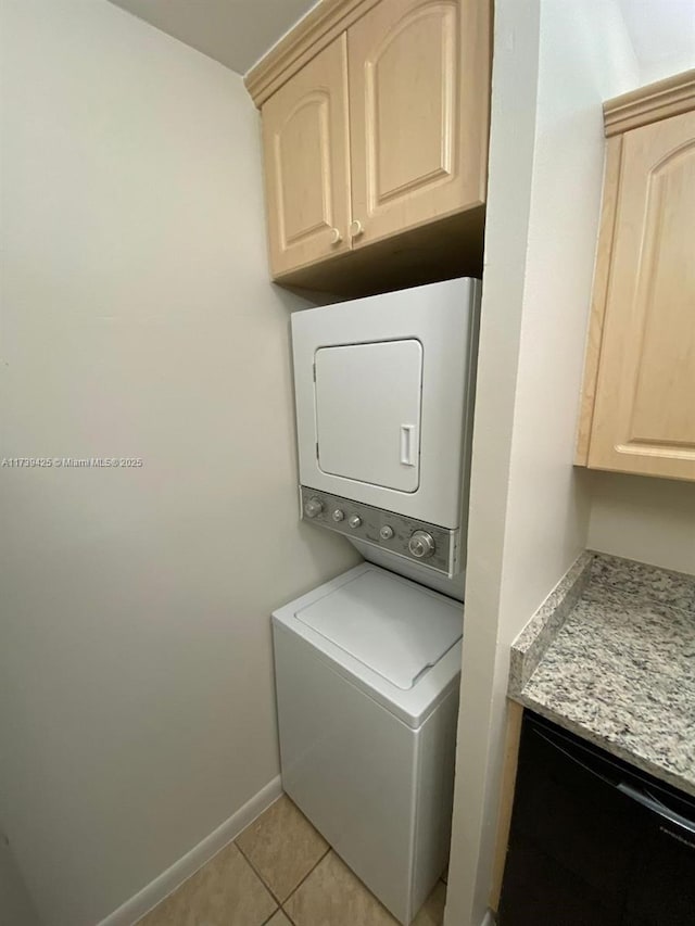 washroom featuring stacked washer and clothes dryer and light tile patterned flooring