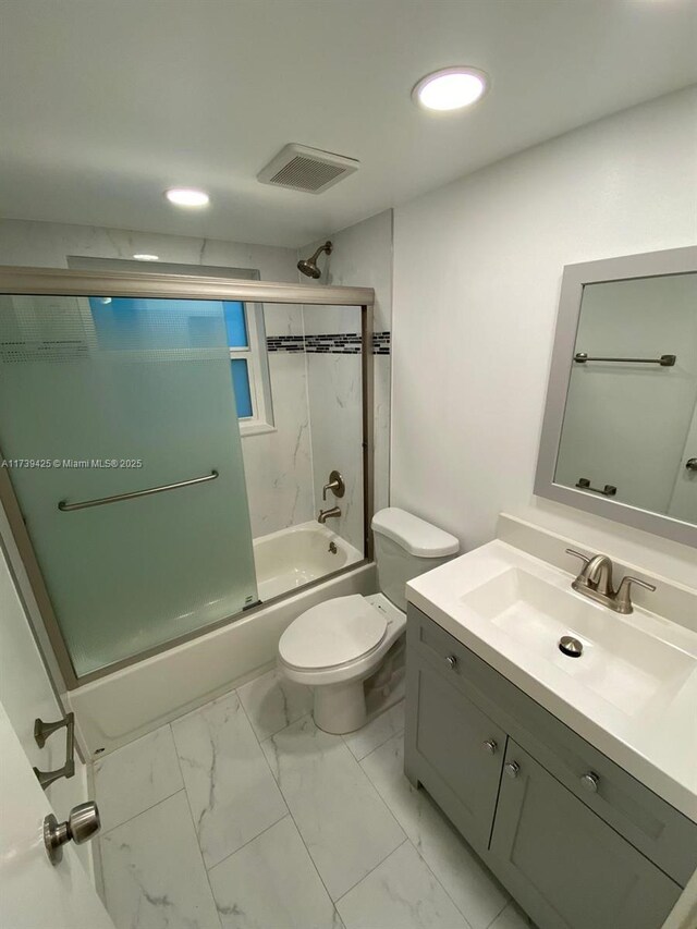 full bathroom with vanity, enclosed tub / shower combo, and toilet