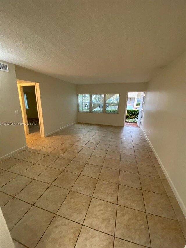 empty room with light tile patterned flooring and a textured ceiling