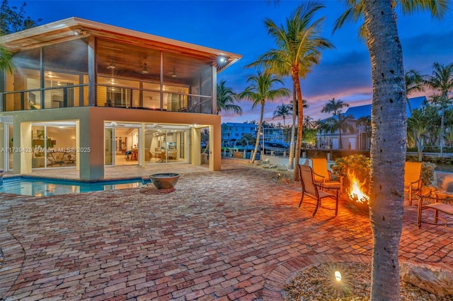 exterior space with a balcony, a sunroom, ceiling fan, and a patio area