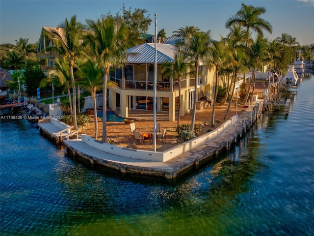 view of dock with a pool, a patio area, and a water view