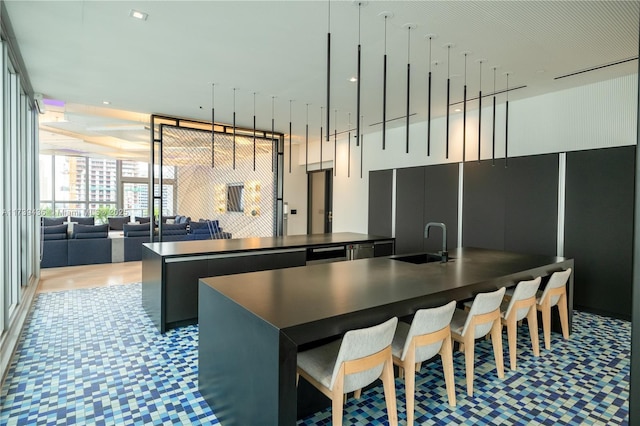 kitchen featuring dishwasher, an island with sink, sink, and floor to ceiling windows