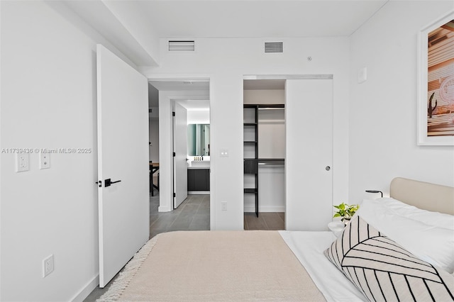 bedroom featuring hardwood / wood-style flooring, ensuite bath, and a closet