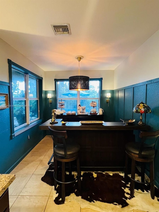 bar with light tile patterned flooring and decorative light fixtures