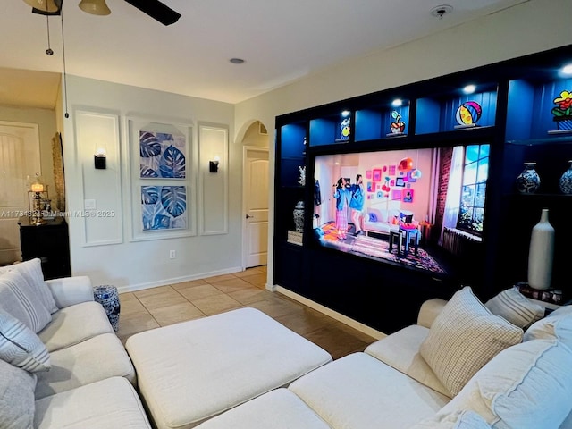 tiled cinema featuring arched walkways, baseboards, and a ceiling fan