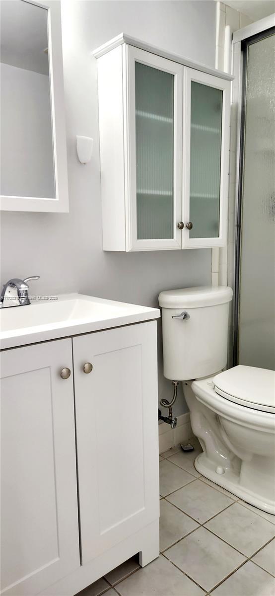 bathroom with vanity, an enclosed shower, tile patterned floors, and toilet