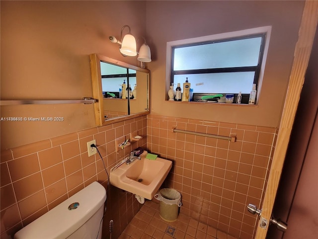 bathroom with sink, tile walls, and toilet