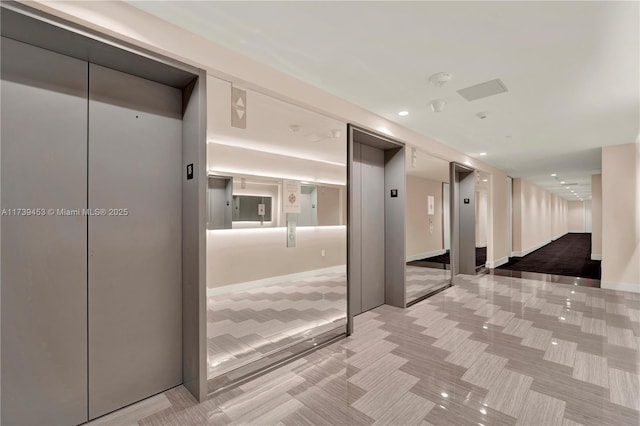 hall with elevator and light colored carpet