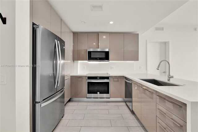 kitchen with gray cabinets, appliances with stainless steel finishes, sink, and kitchen peninsula